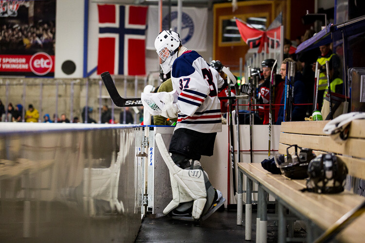 A hockey goalie exits the bench and goes out onto the ice at the start of the game
